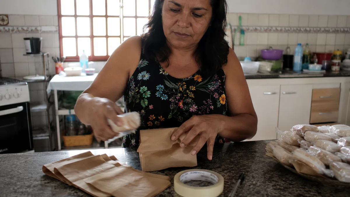 Mulher preparando encomendas em embalagens simples na cozinha de casa